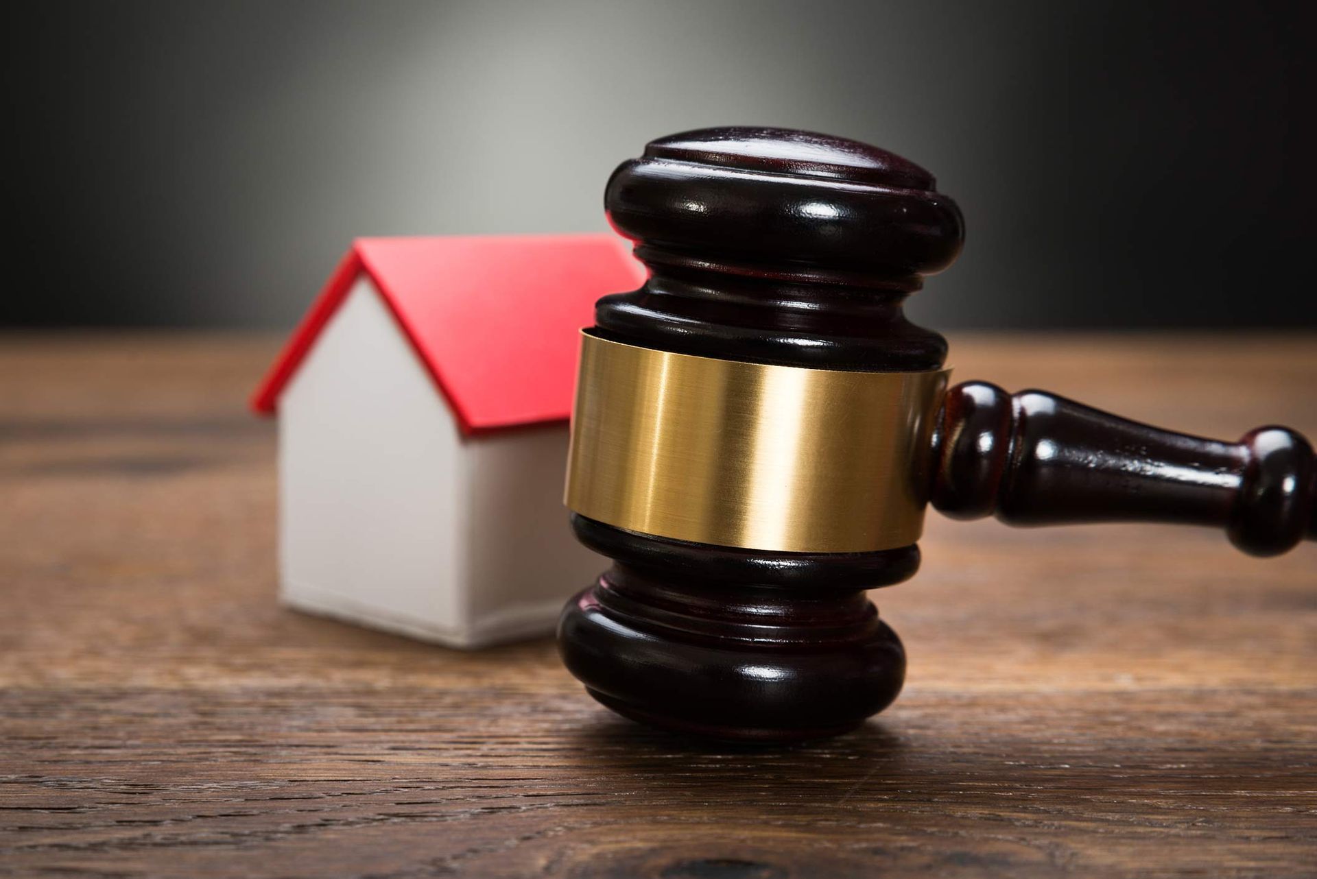 Gavel next to small house model on wooden table, symbolizing real estate law and auctions. Gavel next to small house model on wooden table, symbolizing real estate law and auctions.