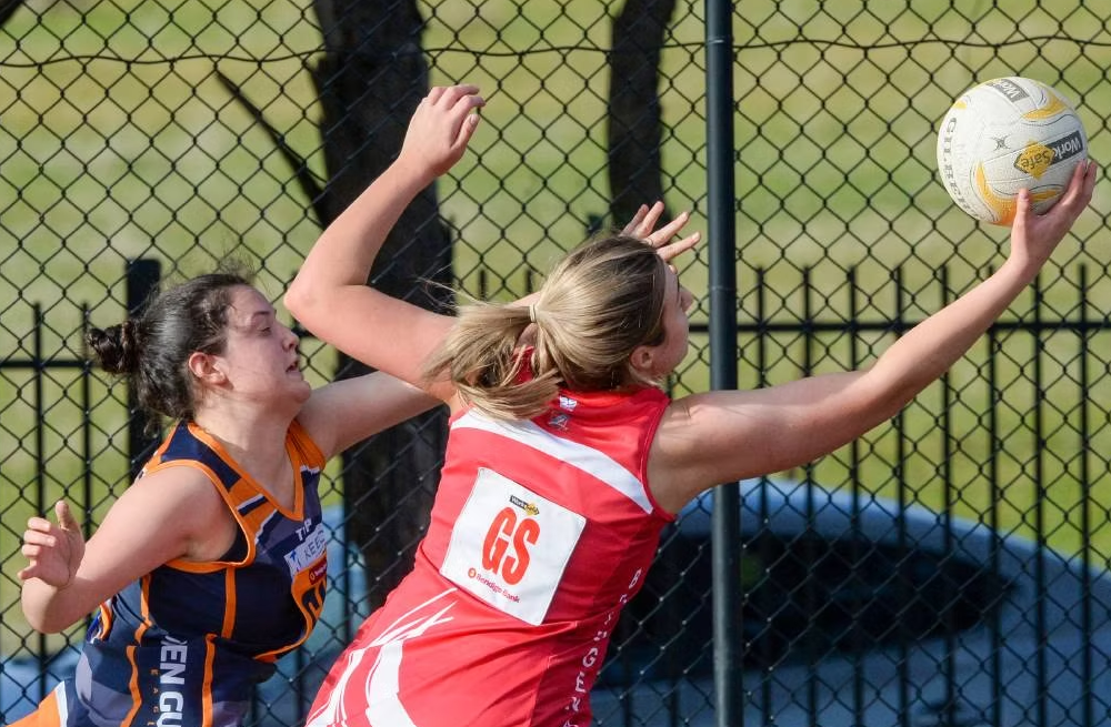 Two women are playing a game of netball and one has the number 69 on her back