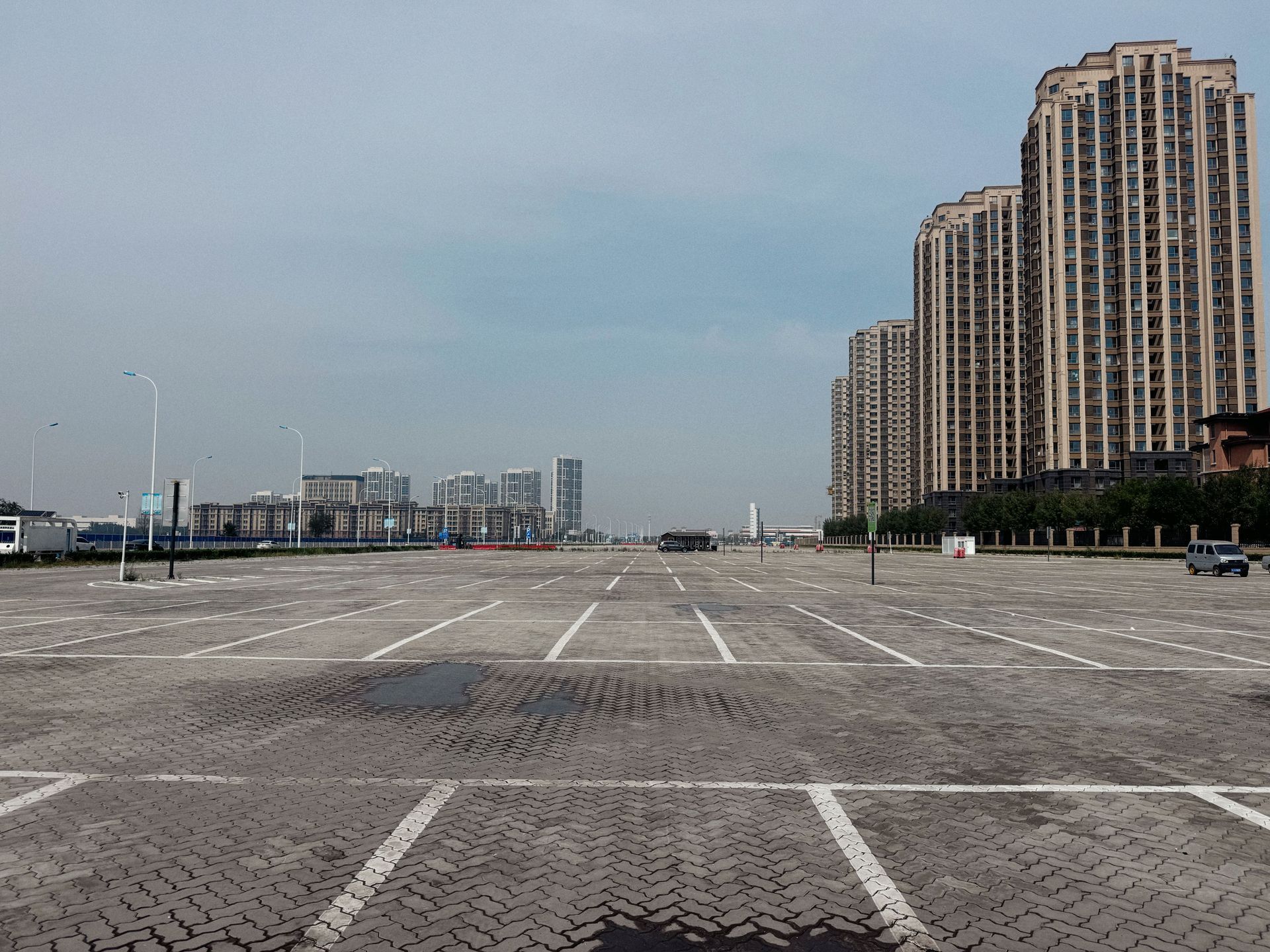 Empty paved plaza beside tall apartment towers under a hazy sky
