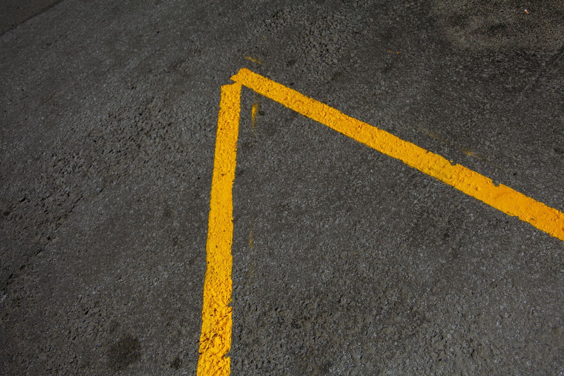 Yellow painted lines on dark asphalt forming an angled corner marking.