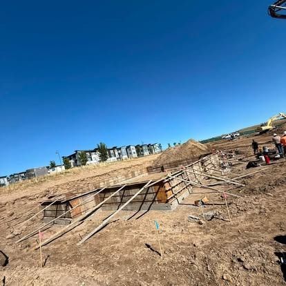 Construction site with rebar foundation, dirt trenches, and blue sky