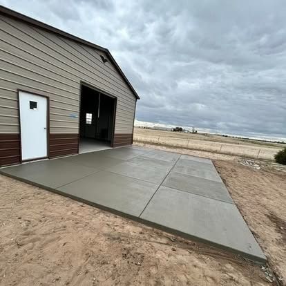 Concrete driveway beside tan metal garage under cloudy sky