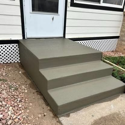 Freshly painted gray concrete steps leading to a white house door
