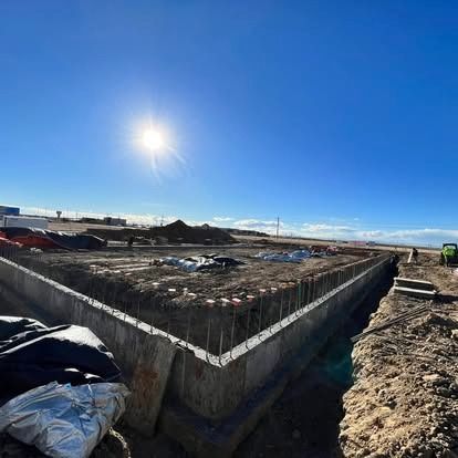 Construction site with concrete foundation under a bright blue sky