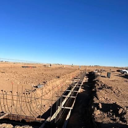 Rebar foundation under construction in a dry field under a clear blue sky