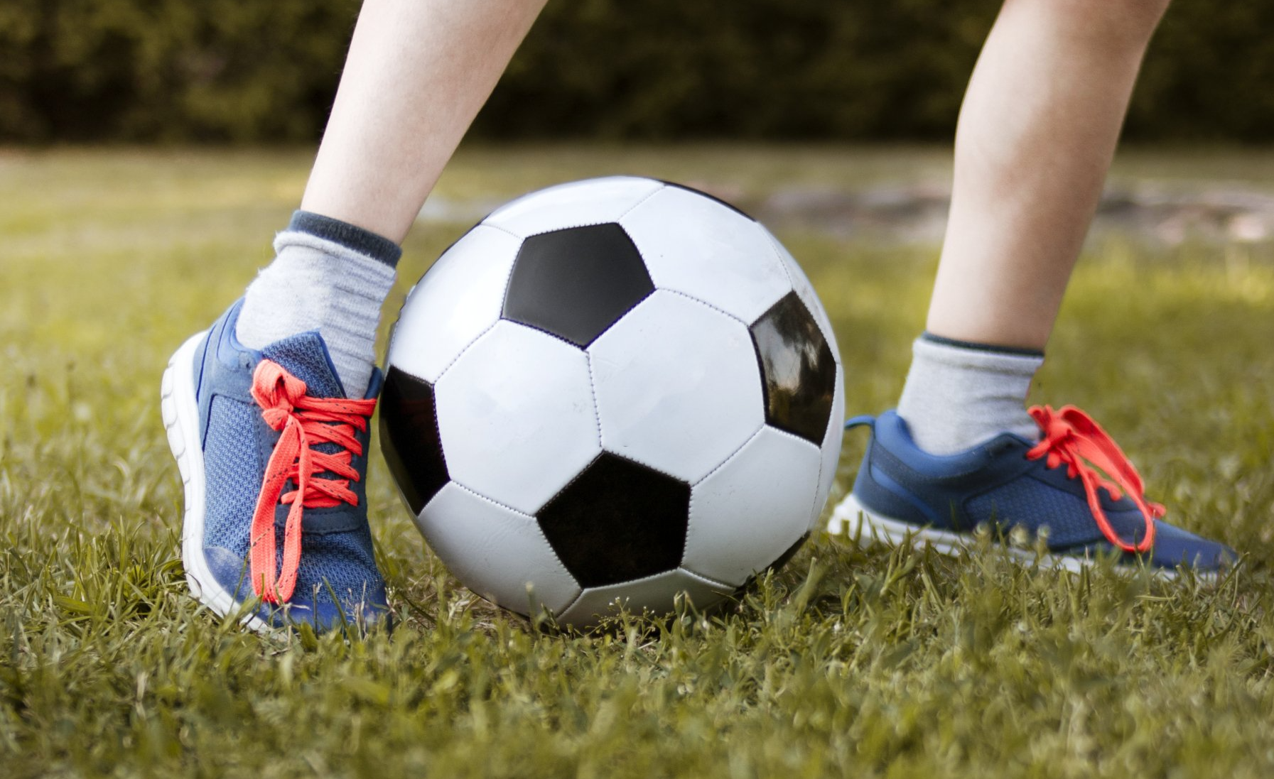 a person is kicking a soccer ball in the grass .