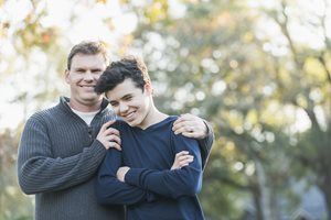 Two people smiling and hugging outdoors in soft sunlight