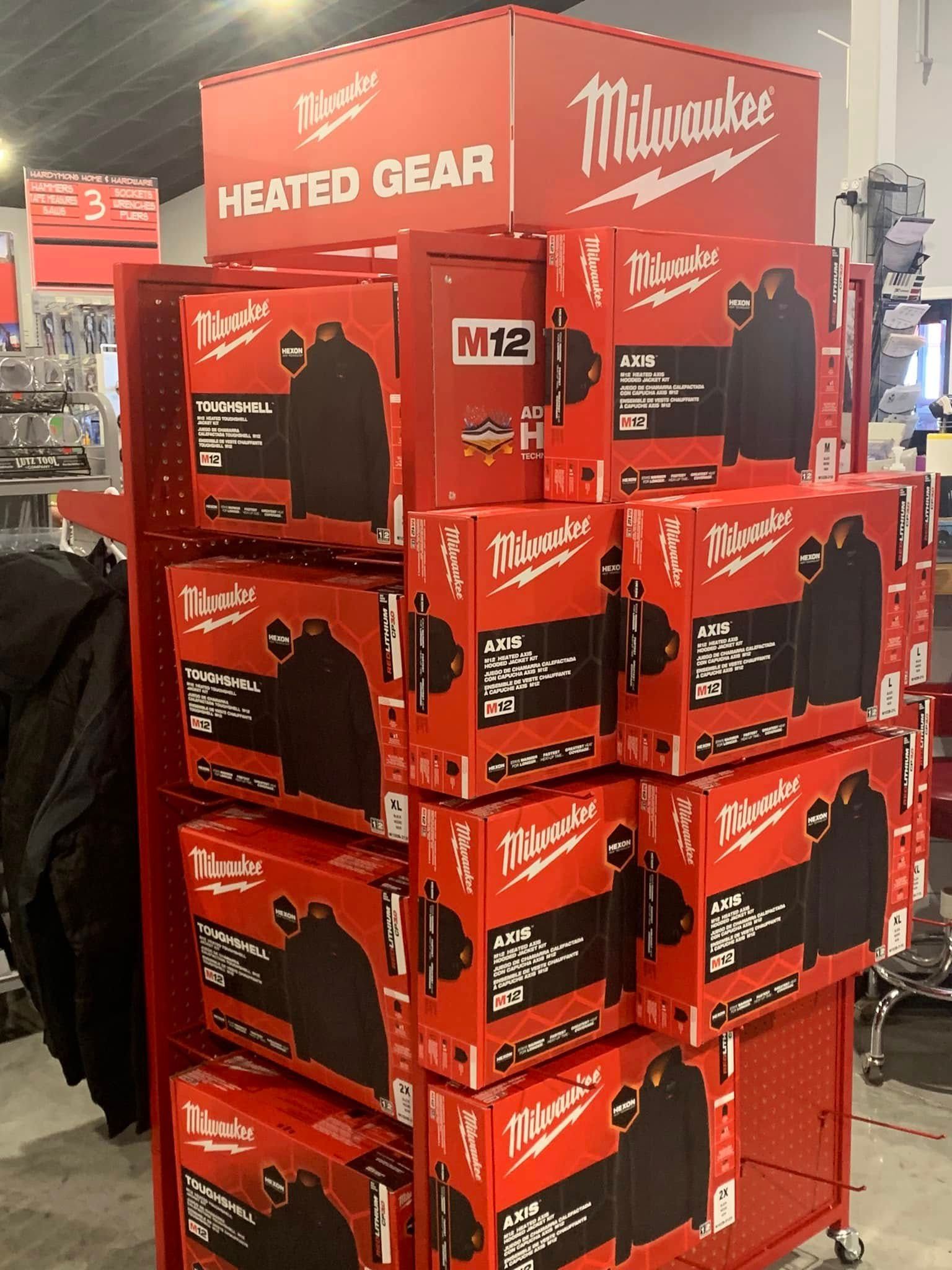Stacked red Milwaukee heated gear display boxes in a store aisle.