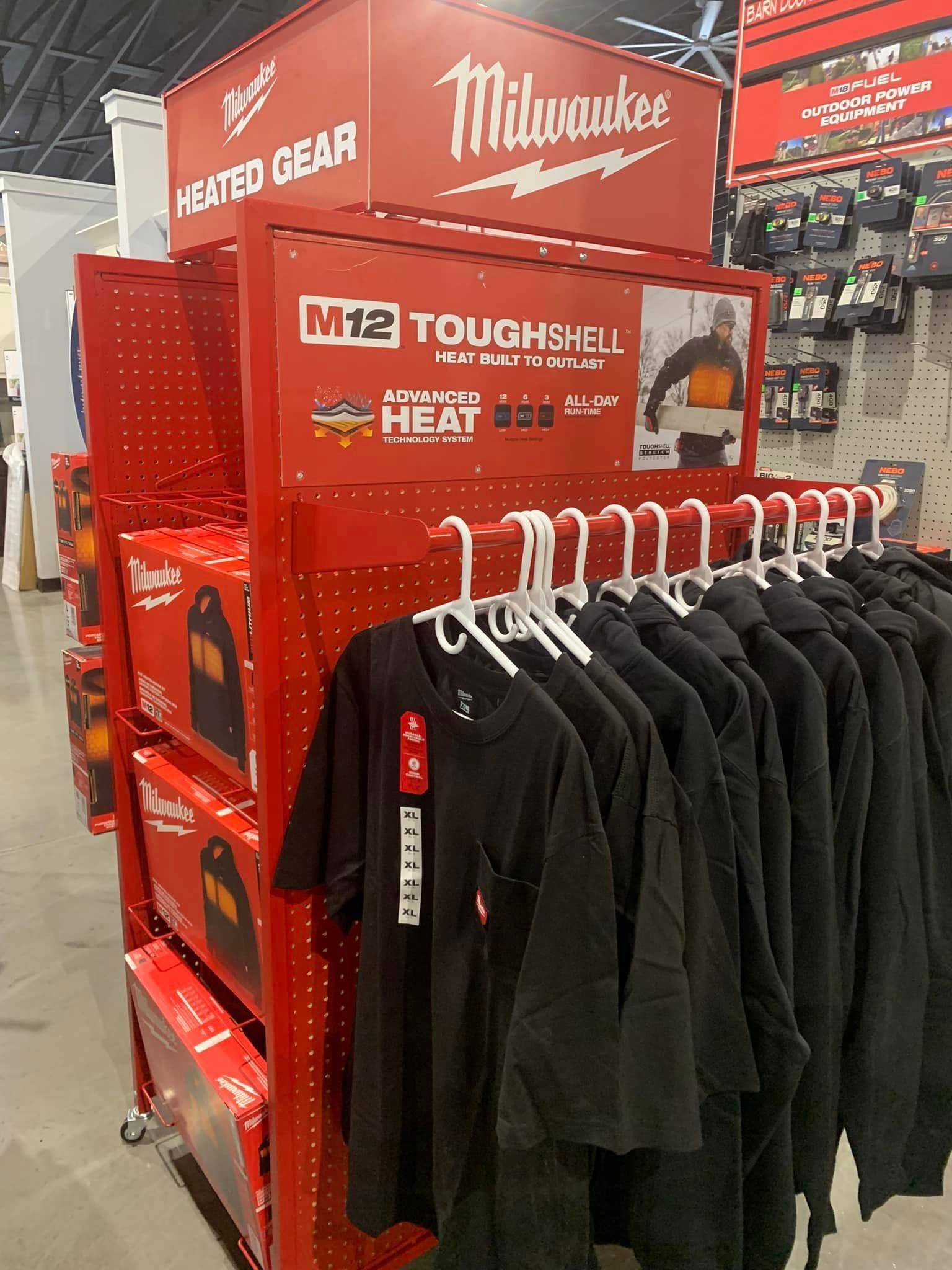 Milwaukee tool display with red ToughShell heated gear and black apparel hanging on racks