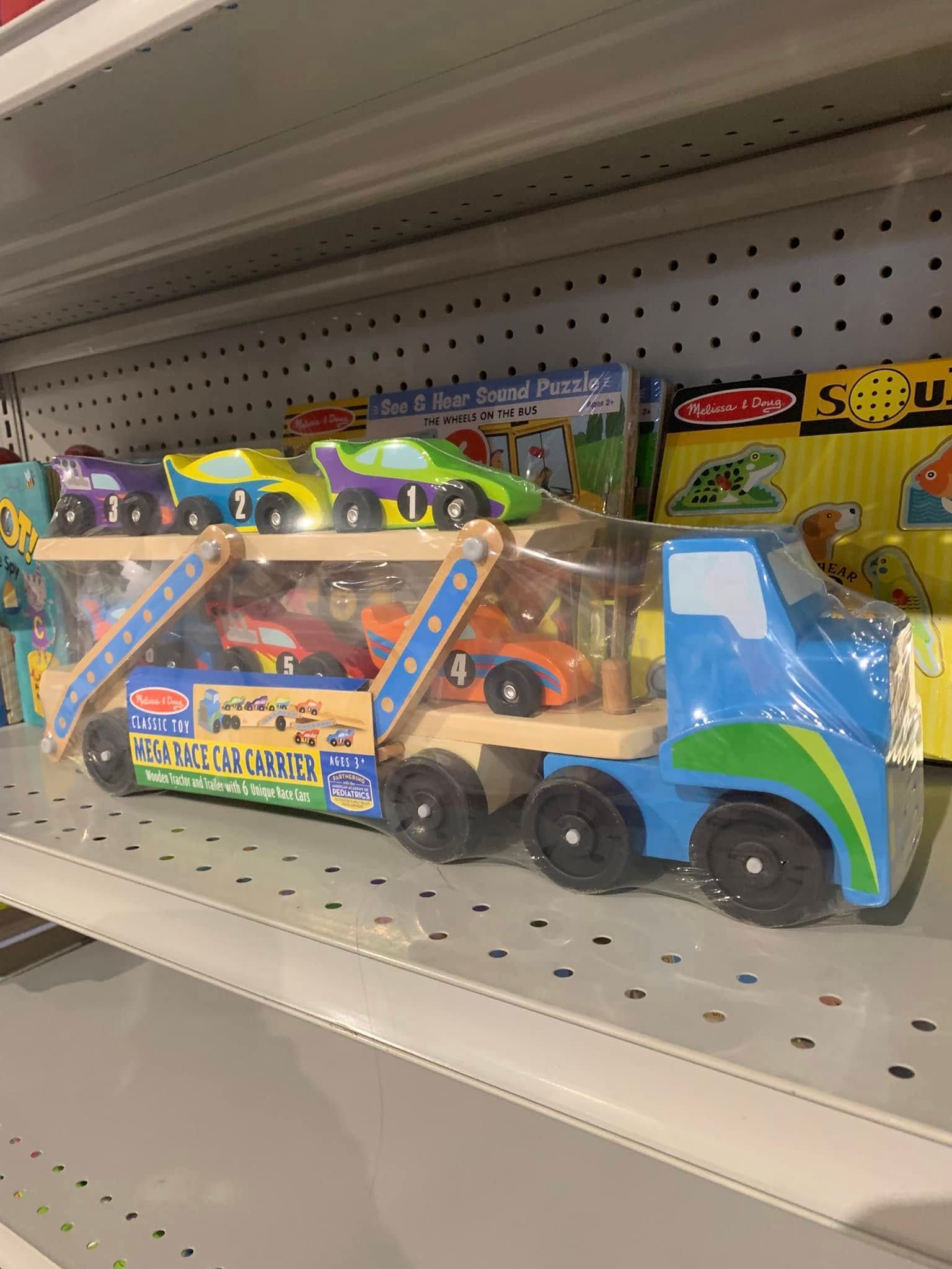 Toy trucks and cars in colorful packaging on a store shelf.