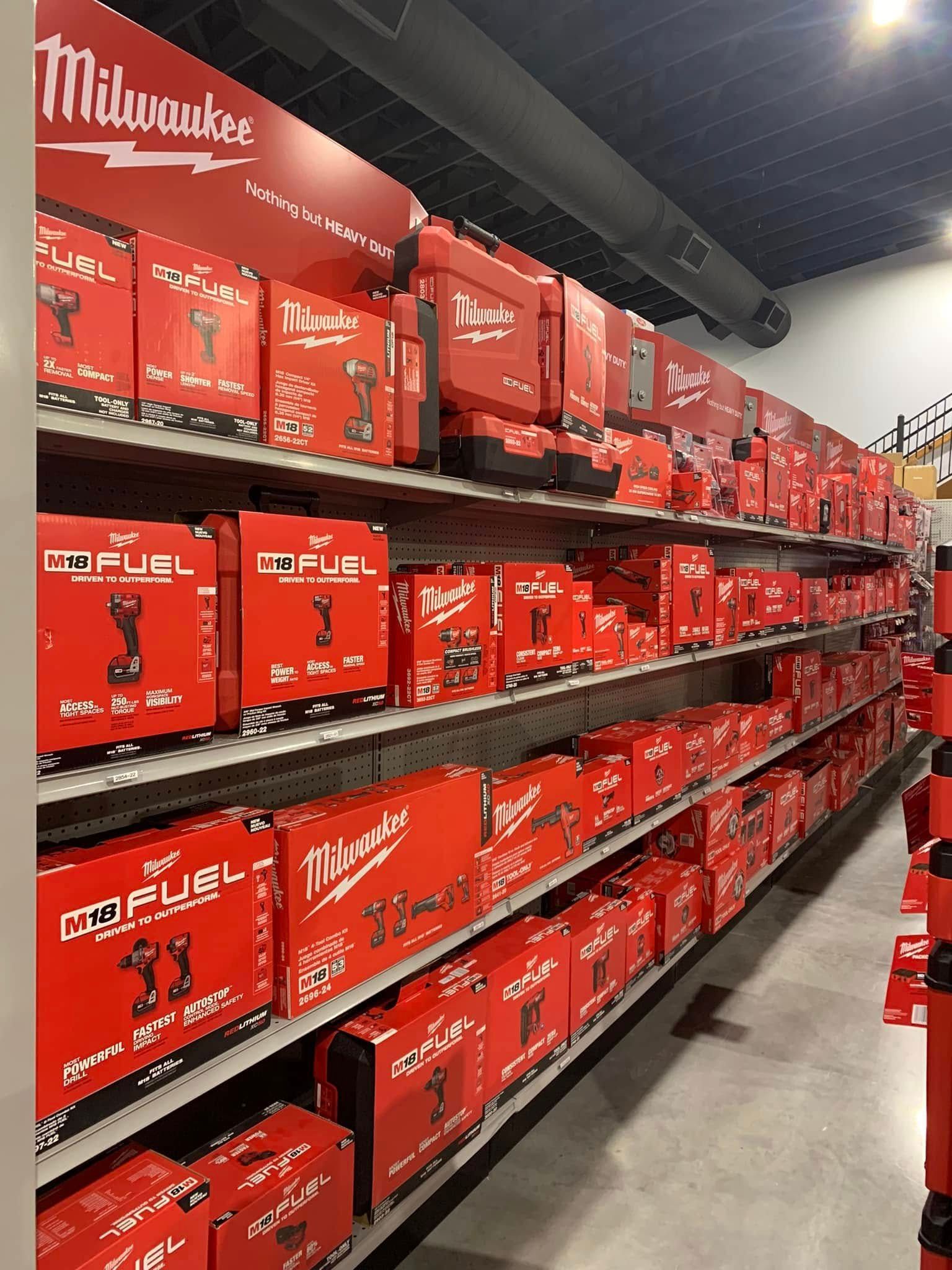 Aisle of red Milwaukee tool boxes stacked on store shelves in a hardware store.