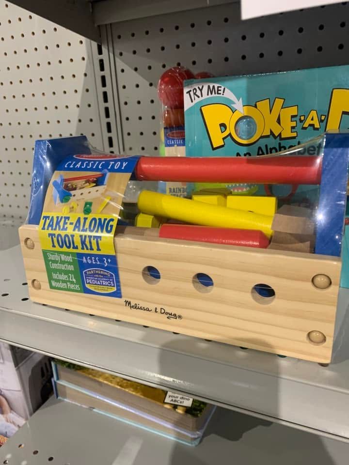 Wooden toy tool kit with colorful tools on a store shelf, beside a Poké Ball toy box.