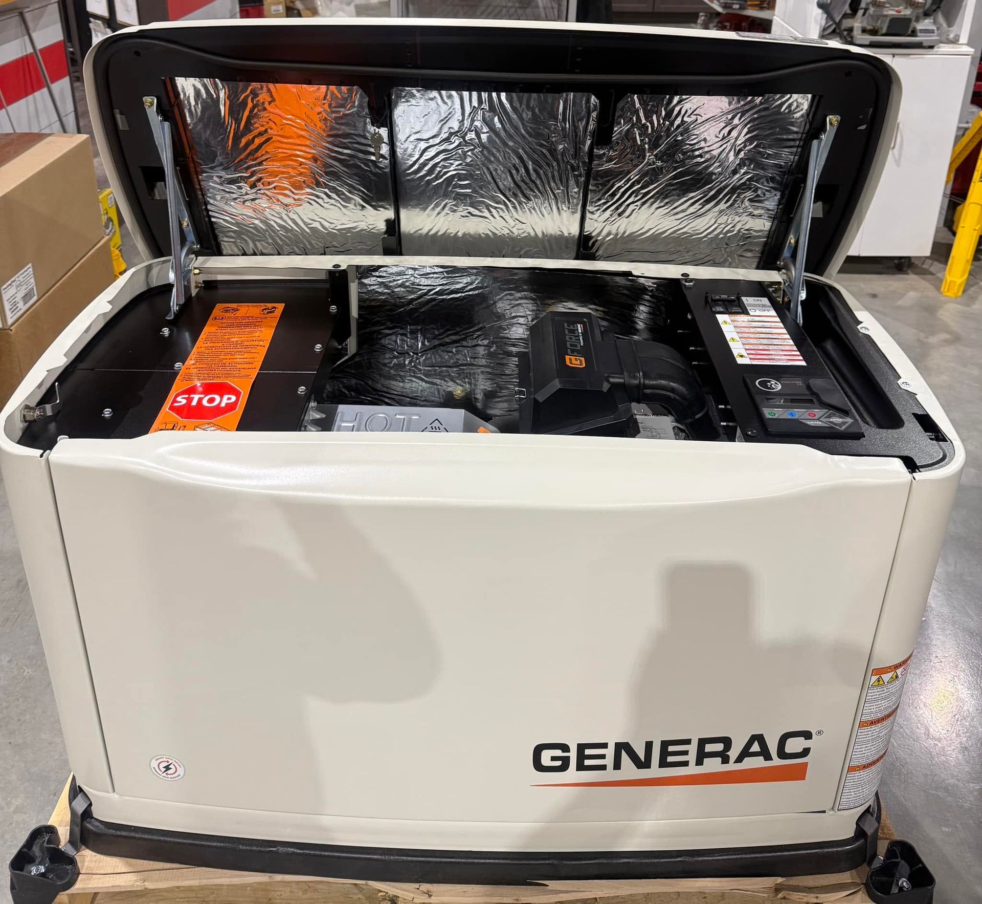 Open Generac portable generator with lid raised, showing engine compartment in a warehouse