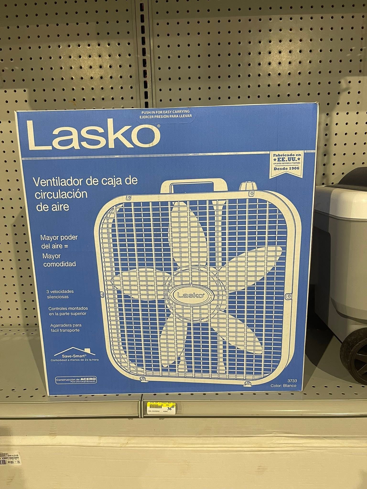 Blue Lasko box with a white box fan shown on a store shelf.