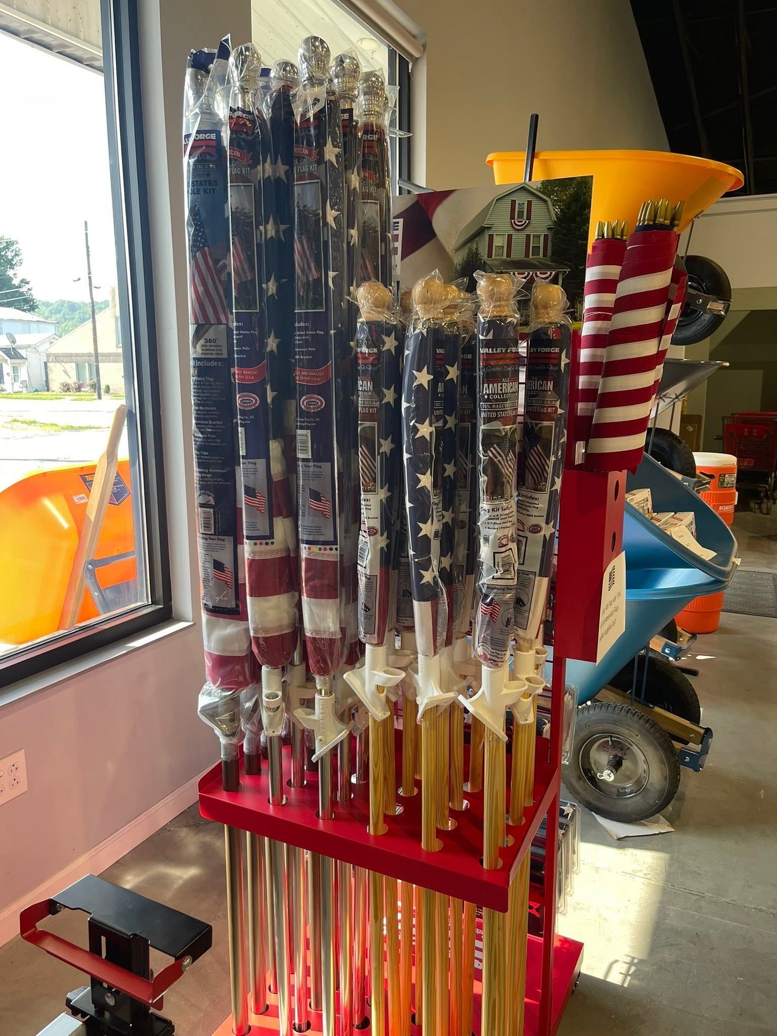 Store rack of star-spangled umbrellas with red and blue handles near a window.