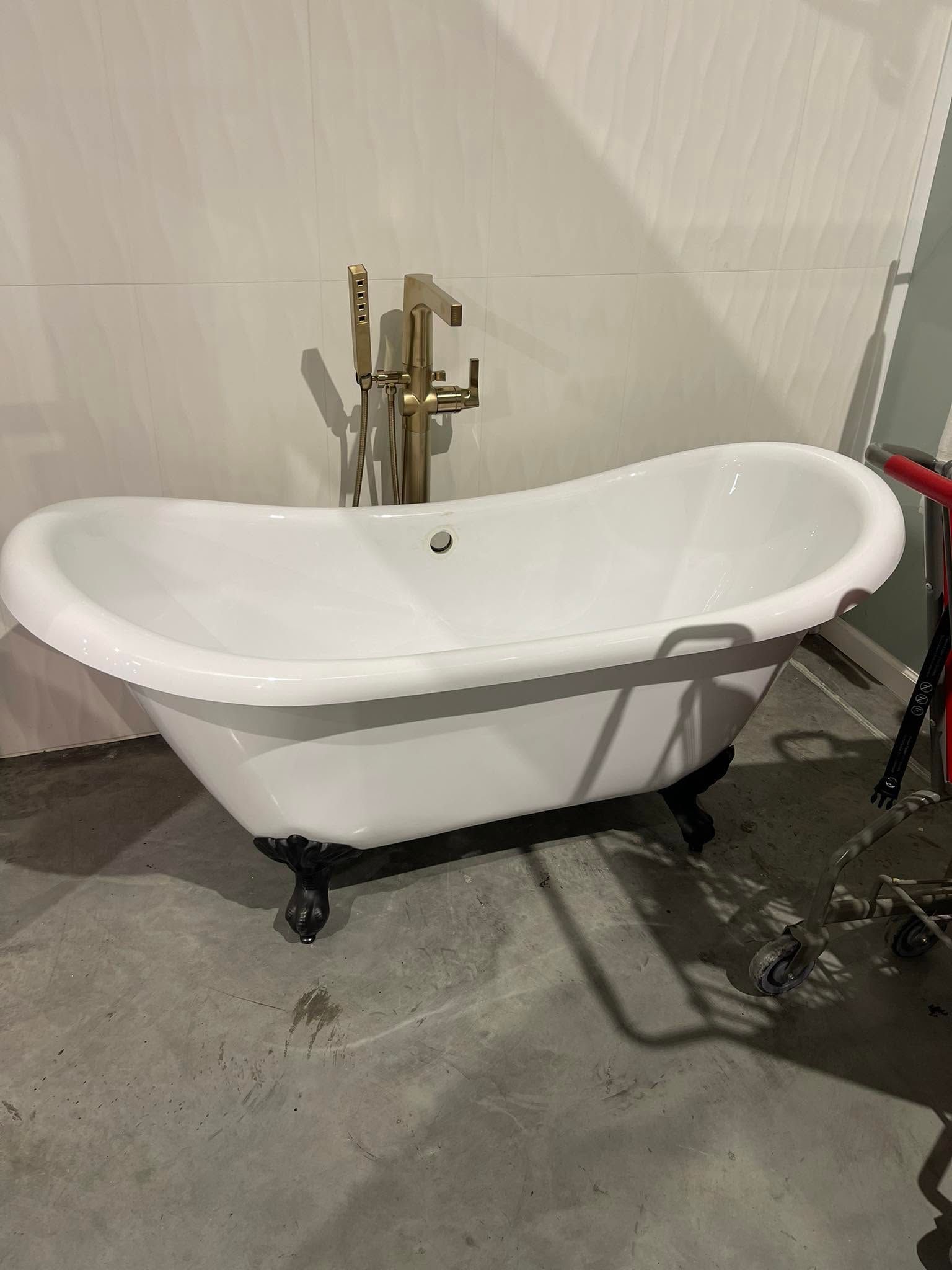 Freestanding white clawfoot bathtub with gold faucet in a bathroom under construction