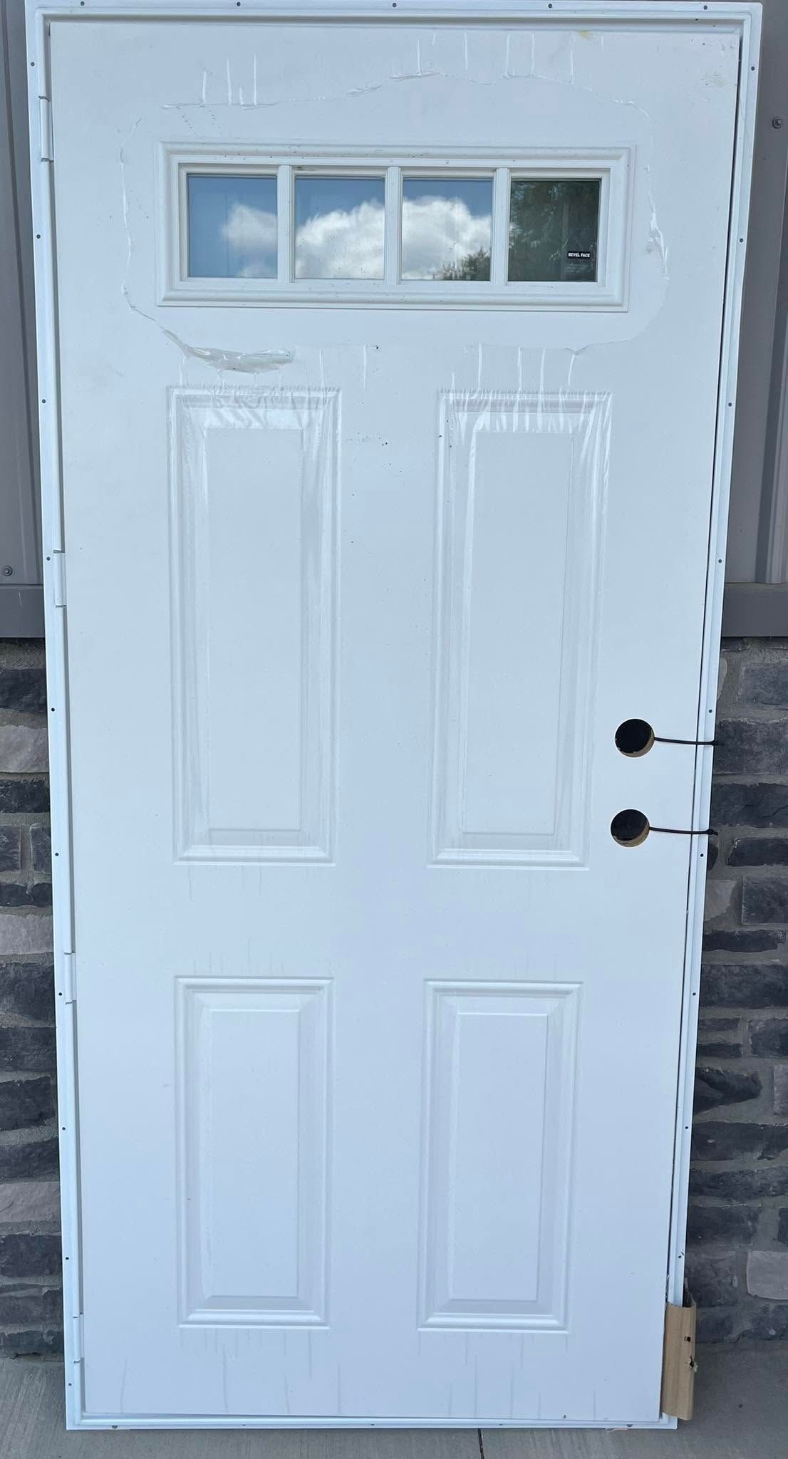 White exterior door with four small windows near the top and a black handle on the right