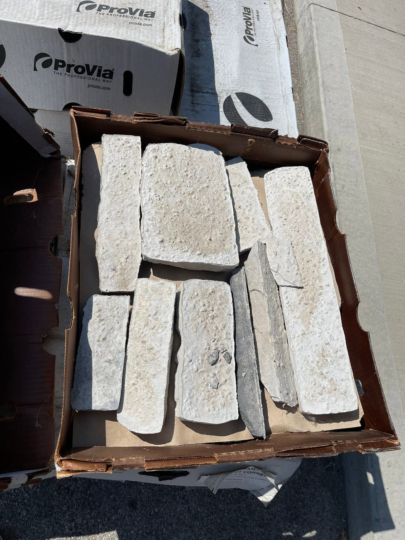 Box of white rectangular foam blocks on a table, with packaging boxes in the background