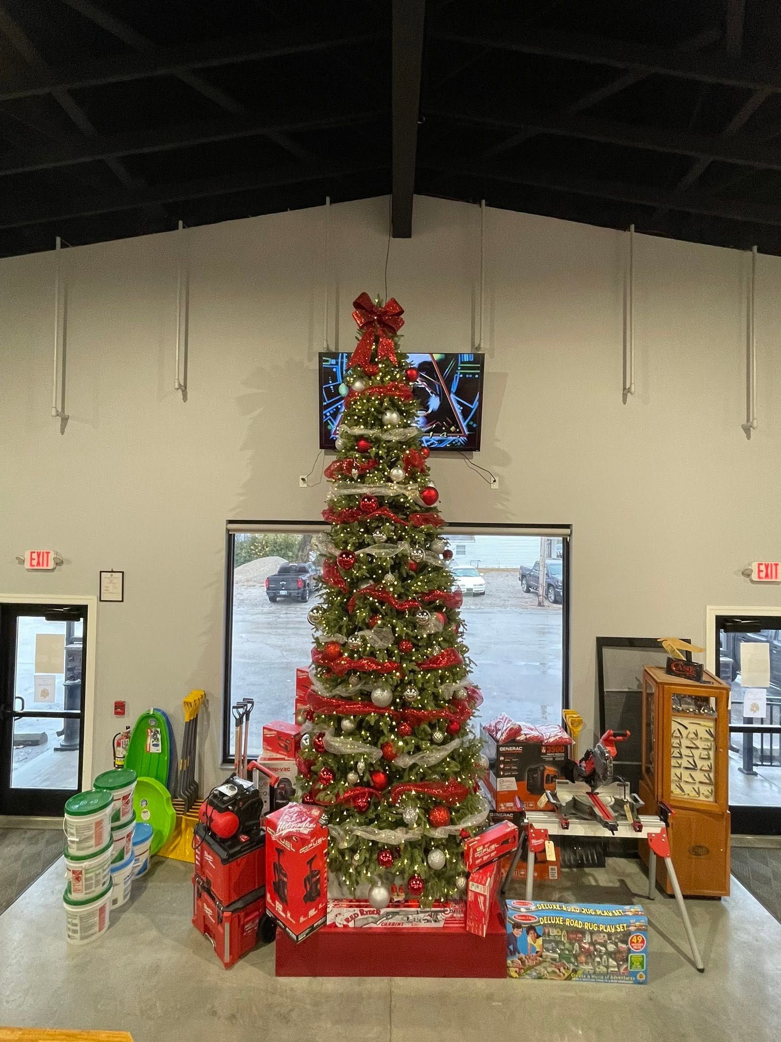 Decorated Christmas tree in a hall, surrounded by wrapped gifts and holiday boxes.