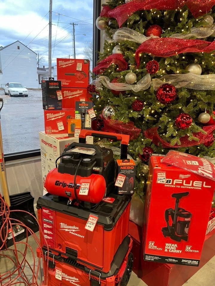 Holiday display with red and black air compressor boxes beside a decorated Christmas tree.