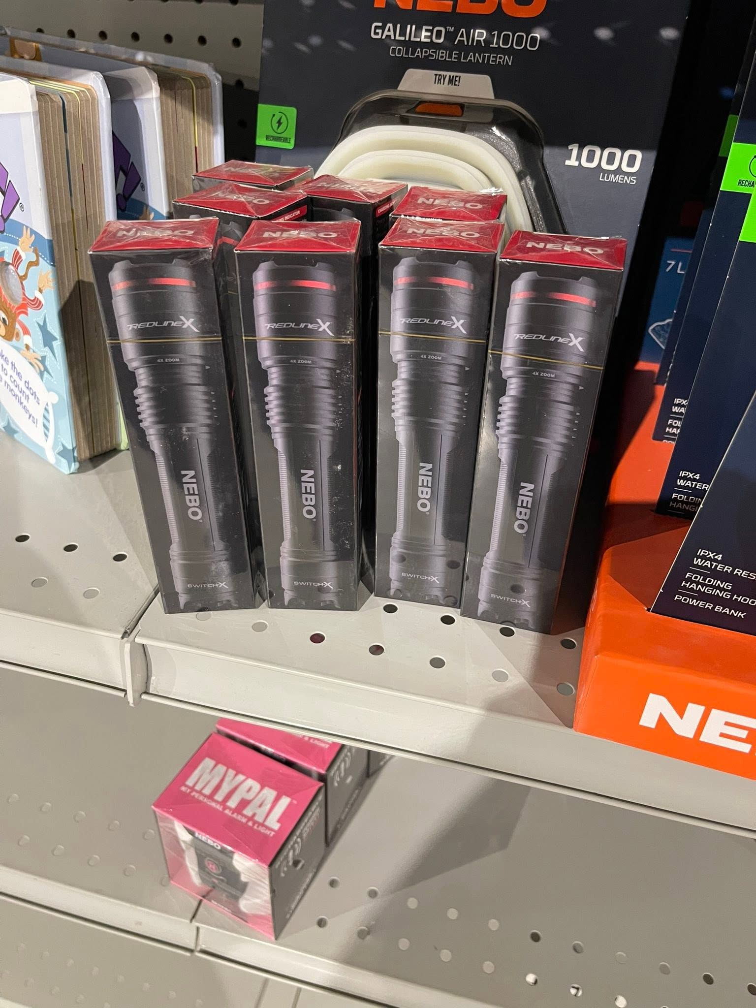 Black packaged items displayed on a store shelf with pink and red labels.
