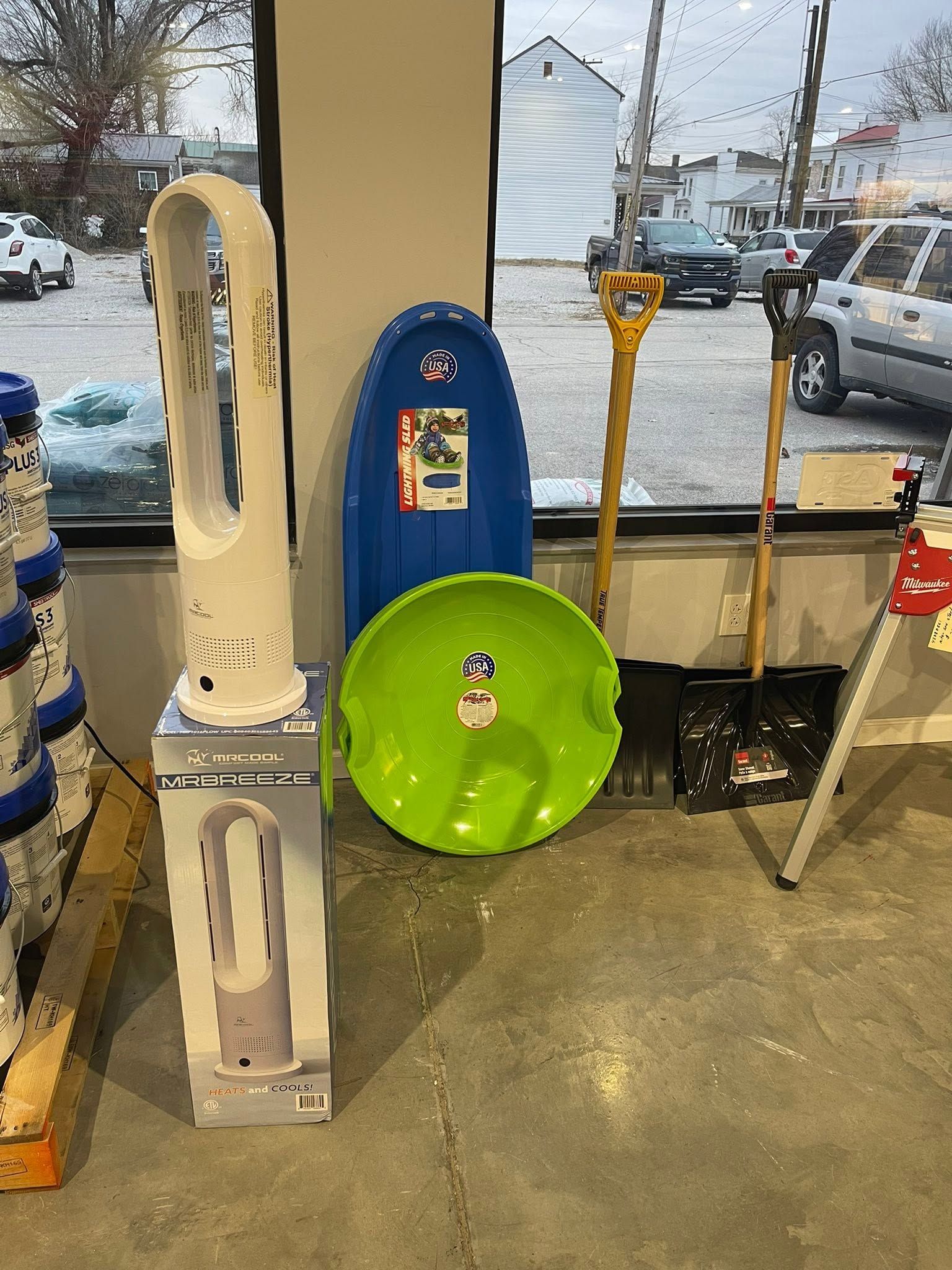 Display of colorful plastic tunnel toys and a small table inside a storefront near a snowy parking lot.