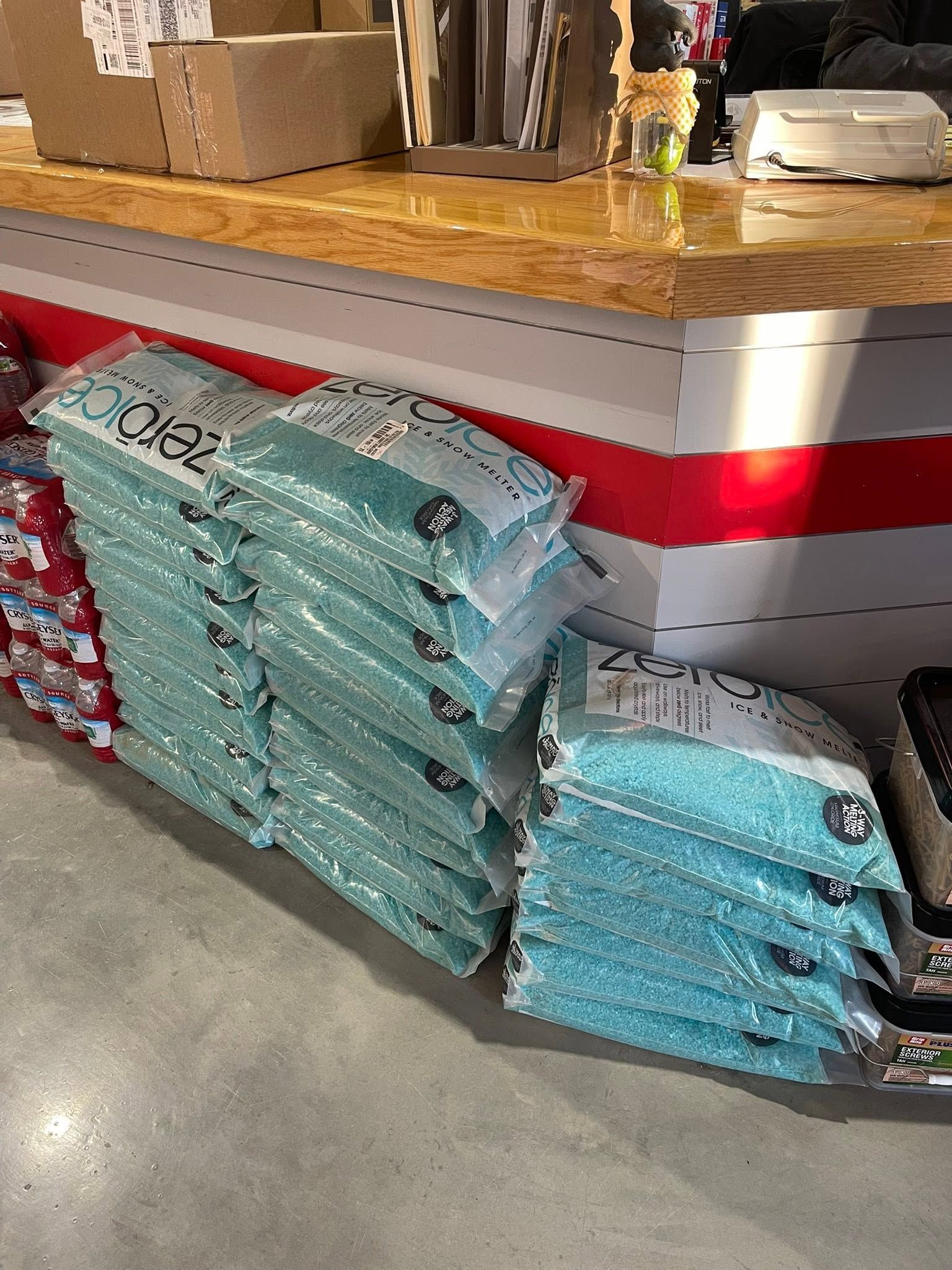 Stacked blue pet supplies bags beside a retail counter with a wooden top and red stripe.