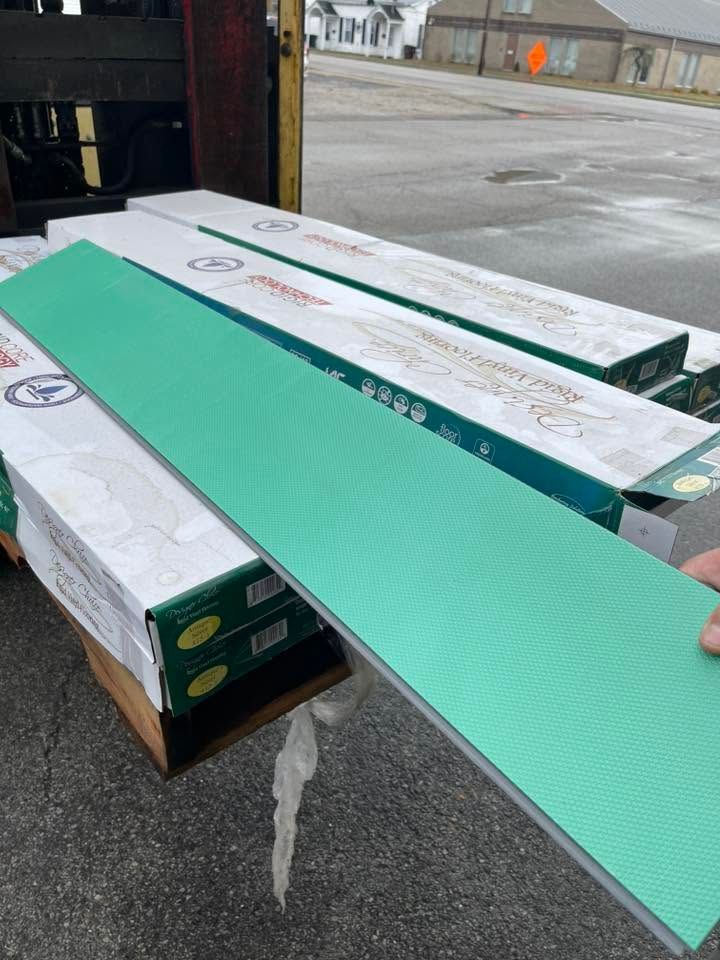 Green flooring plank on stacked boxes in a warehouse loading area