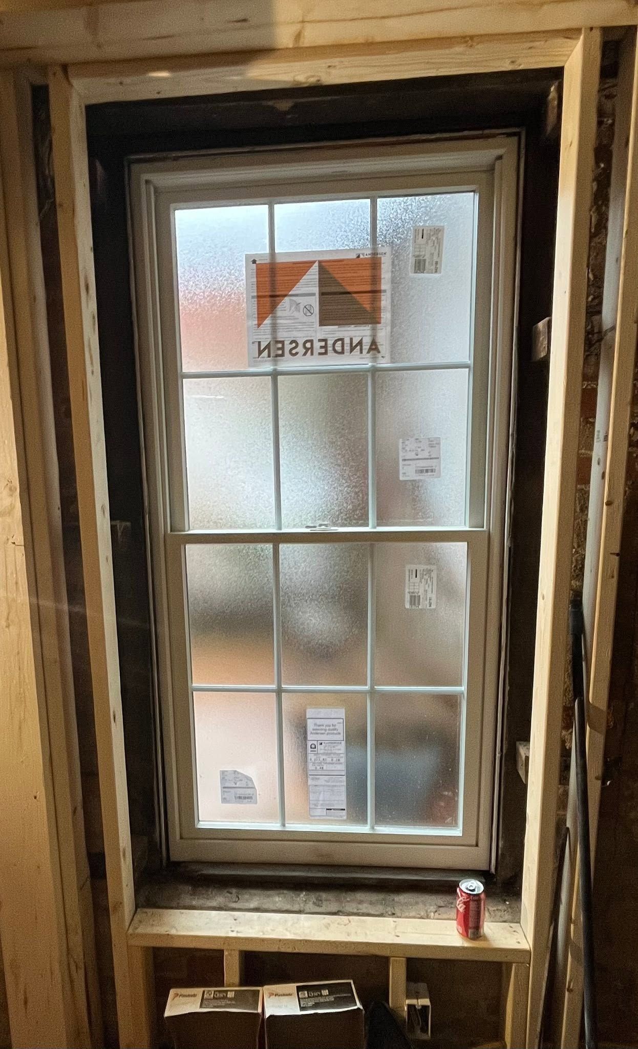 Old wooden window with frosted panes in an unfinished wall, with a red can on the sill.