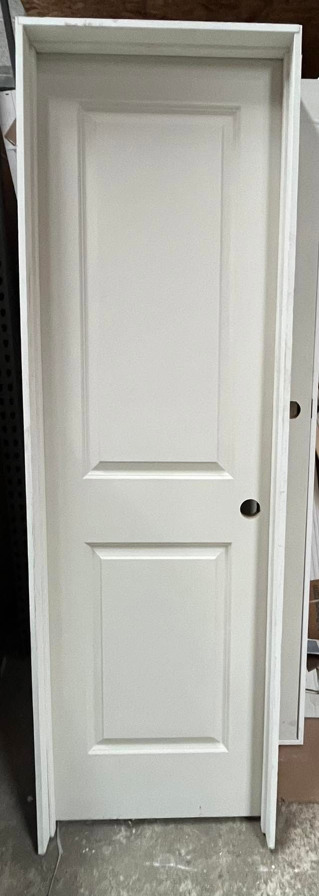 White interior door in a doorway, with simple panel design and black knob.
