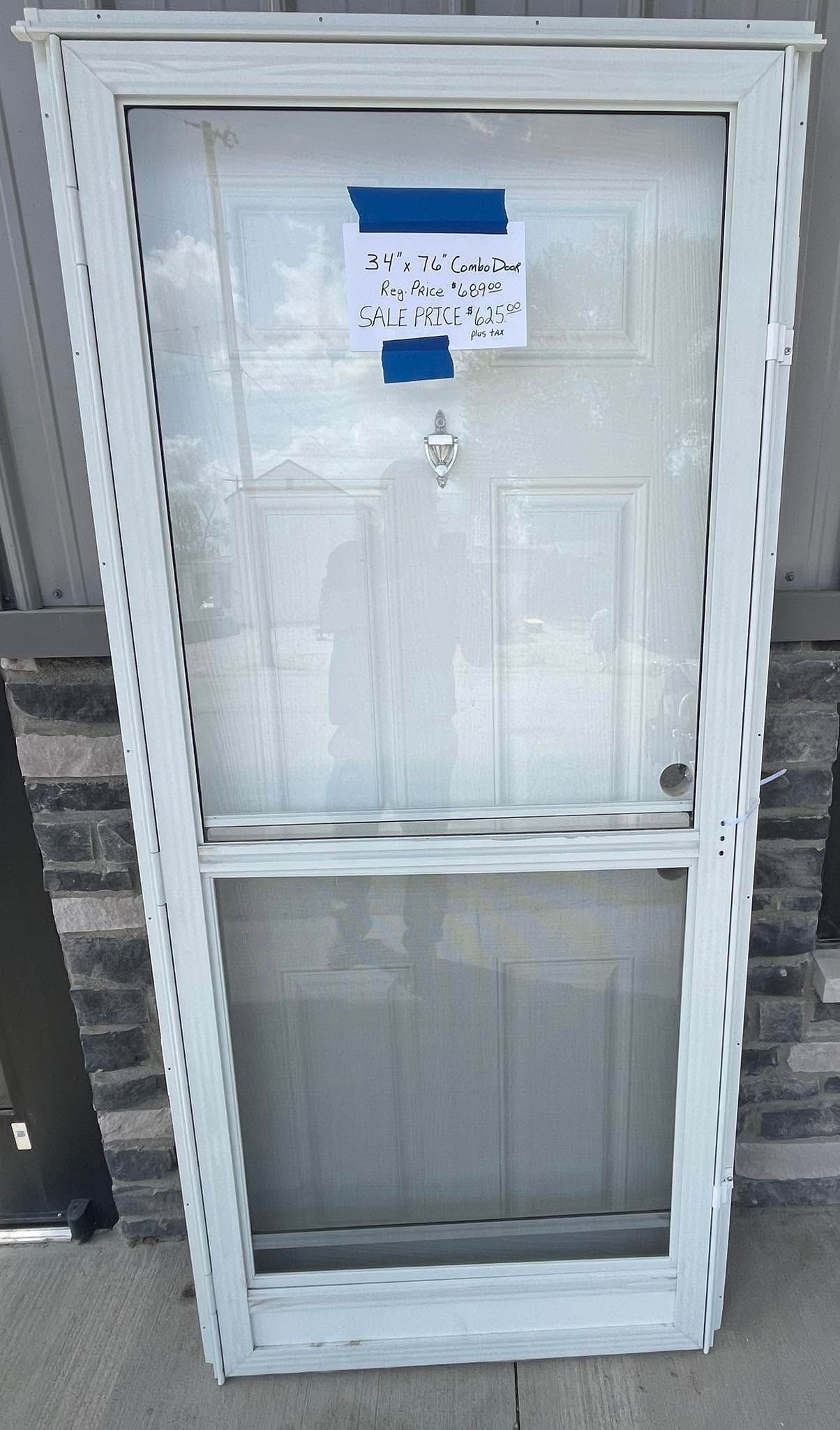 White framed door or window panel leaning upright against a wall, with a blue label near the top.