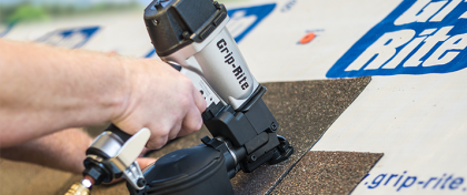 Hand using a brad nailer to fasten dark flooring over a light work surface, with Grip-Rite logo visible
