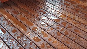 Wet wooden deck with scattered water droplets and reflections after rain