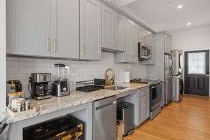 Modern kitchen with gray cabinets, granite counters, stainless appliances, and a hardwood floor