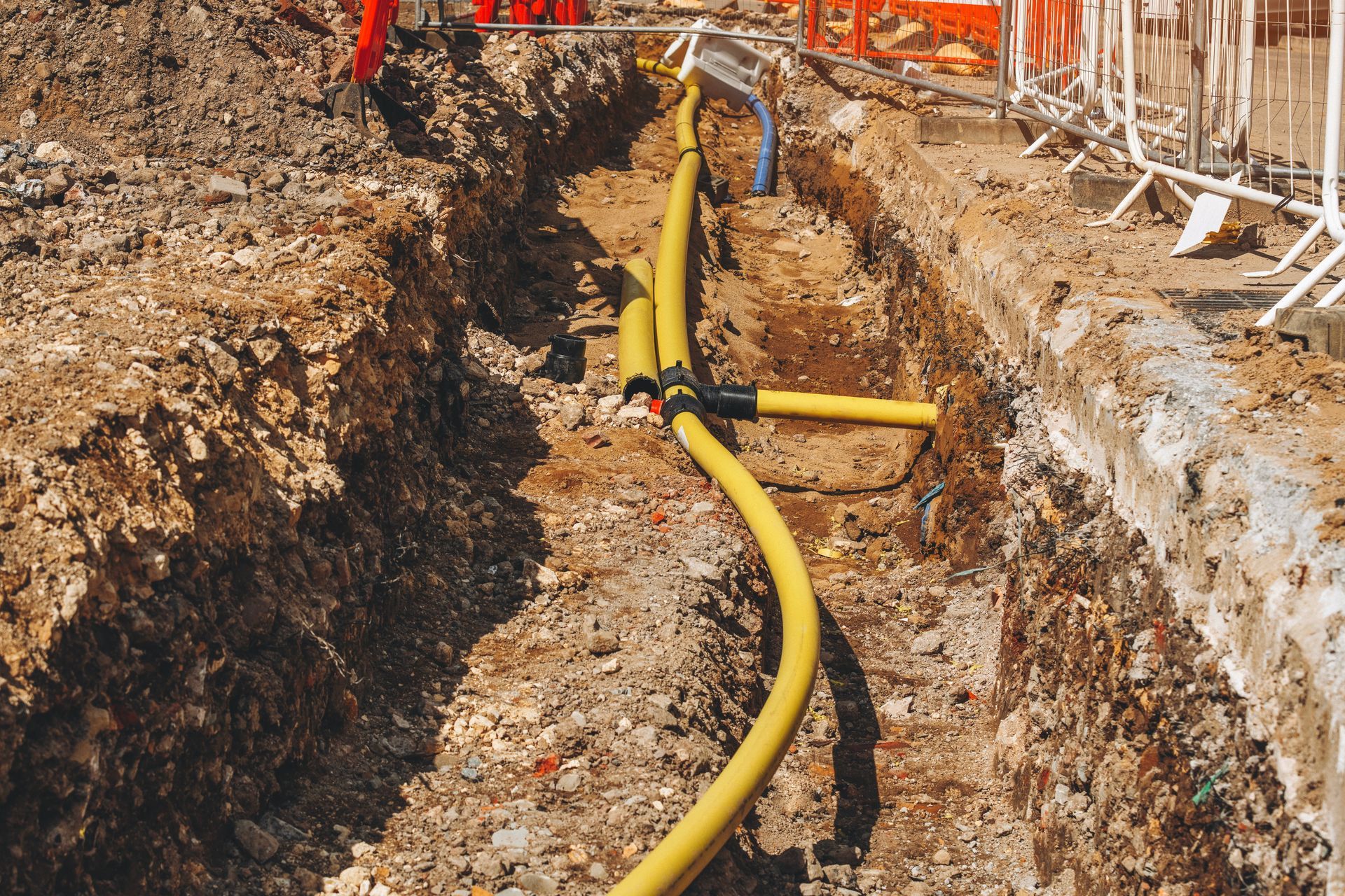 Yellow gas pipe laid in a dirt trench at a construction site