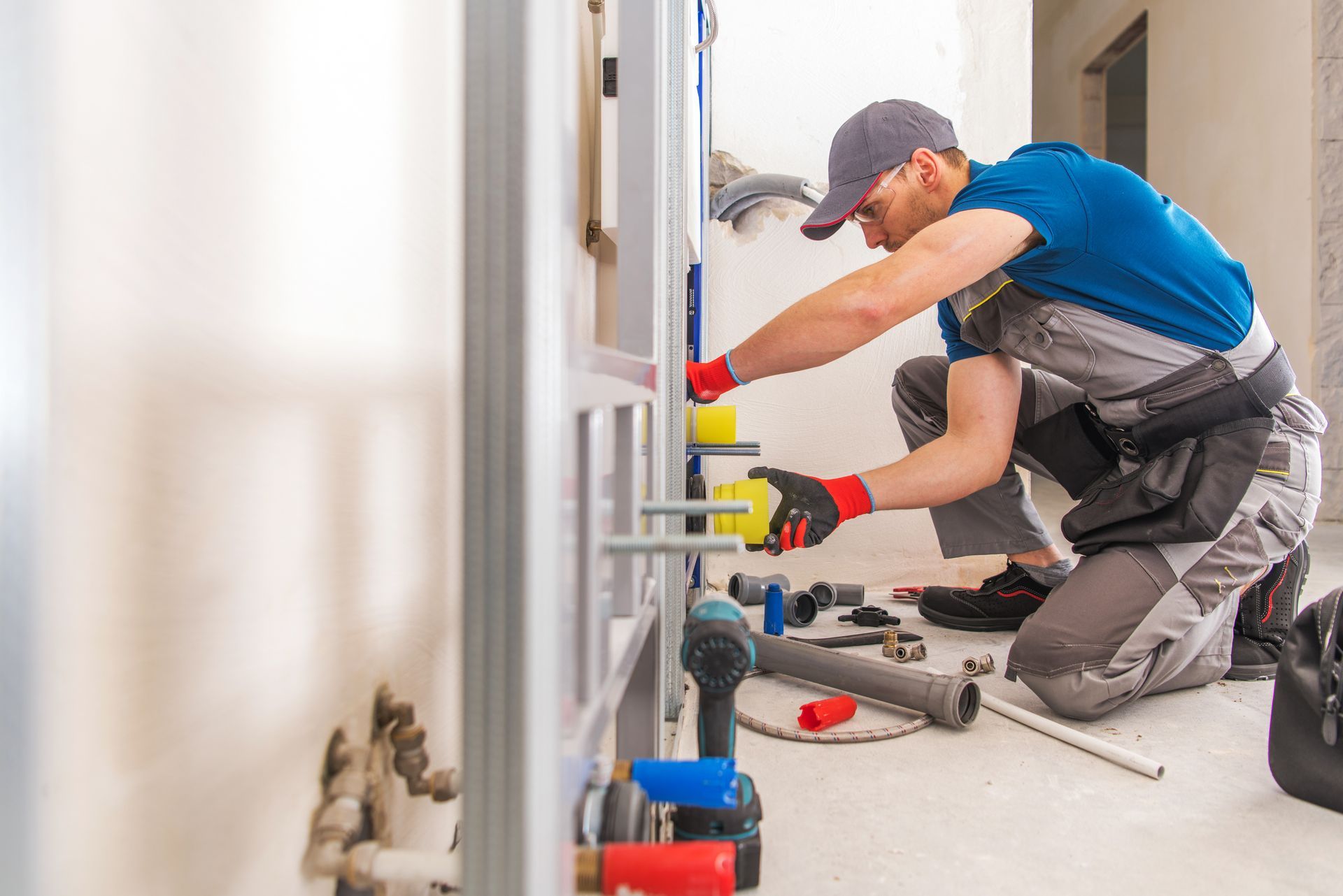 Plumbers repairing bathroom pipes under a sink, using tools and wearing work gloves and caps Plumbers repairing bathroom pipes under a sink, using tools and wearing work gloves and caps