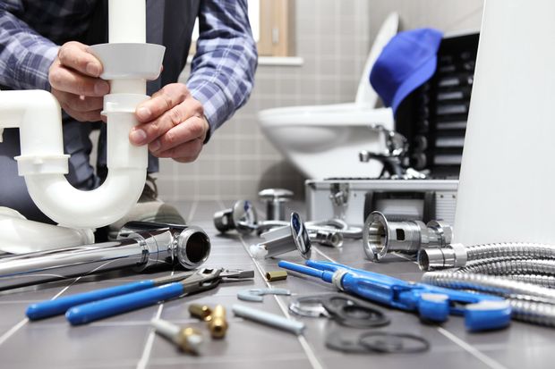 Plumber assembling white PVC pipe with blue-handled tools on a workbench Plumber assembling white PVC pipe with blue-handled tools on a workbench
