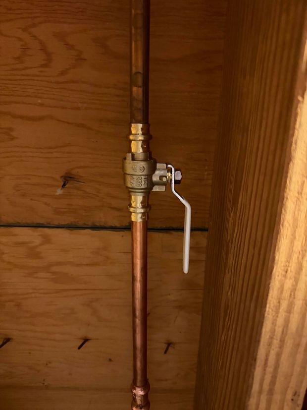 Copper pipe with a brass shutoff valve mounted against a wooden wall. Copper pipe with a brass shutoff valve mounted against a wooden wall.
