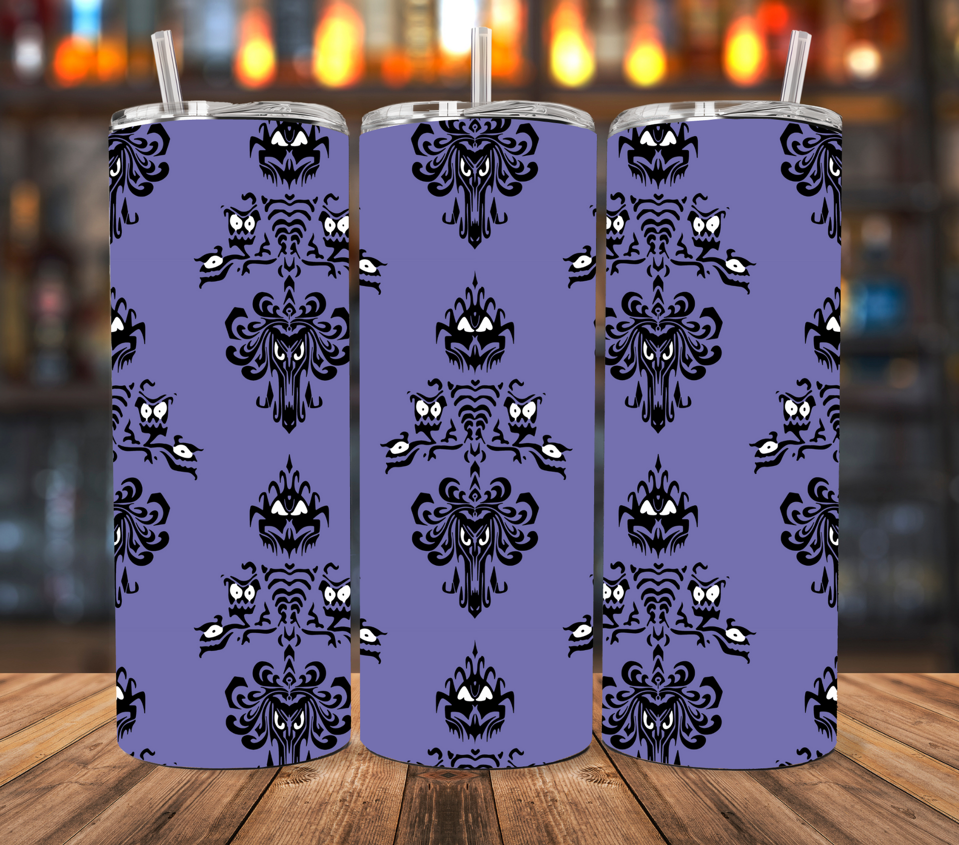 Three stainless steel tumblers stand on a wooden surface, featuring the purple Haunted Mansion wallpaper pattern.