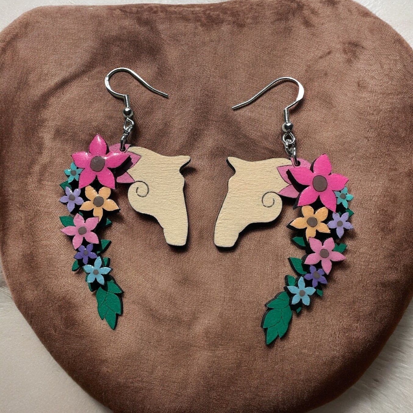 Pair of wooden horse head earrings decorated with colorful pink, orange, blue, and purple floral accents.