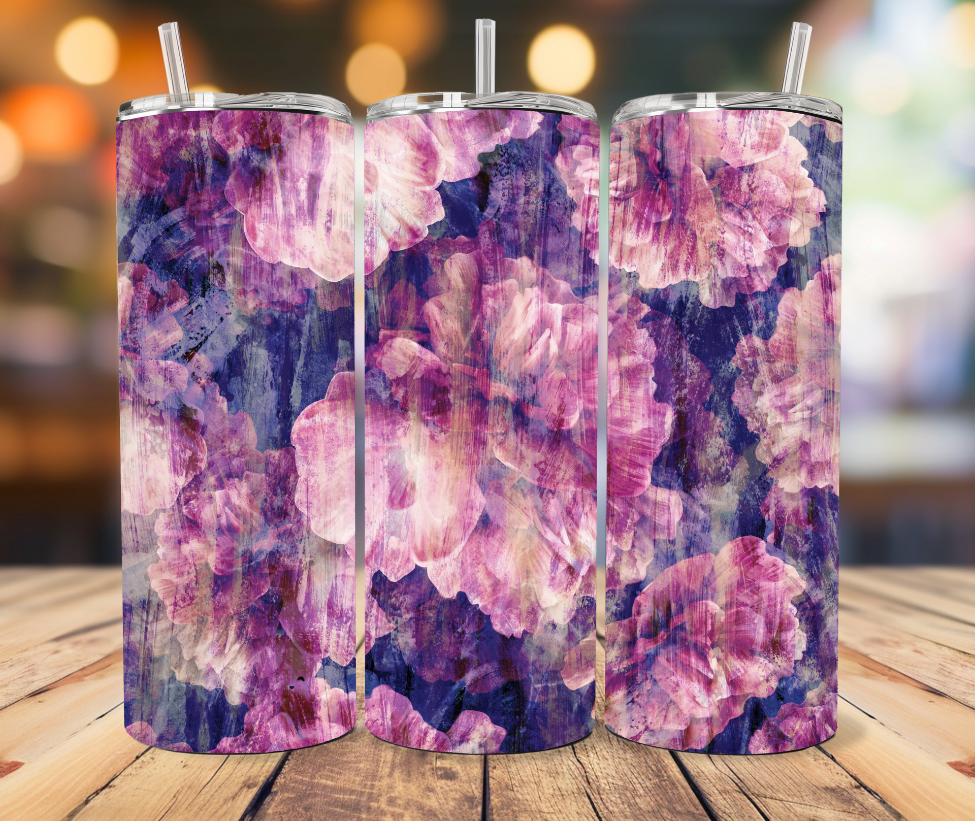 Three tumblers with purple and pink floral patterns standing on a rustic wooden surface against a bokeh background.