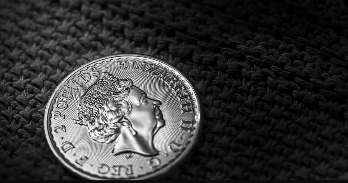 Close-up of a silver coin with a profile portrait on a dark textured fabric background