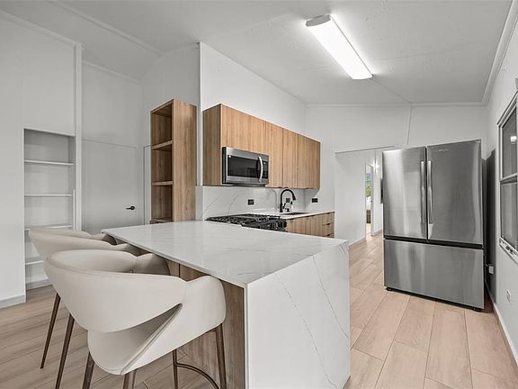 Kitchen with a quartz island, gas range and stainless refrigerator