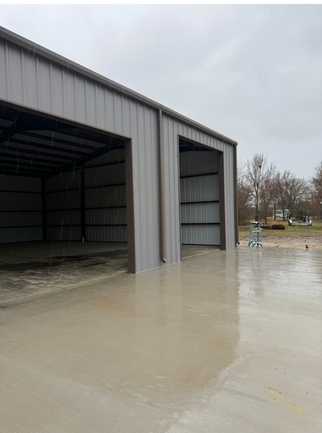 Flooded metal warehouse with muddy water pooled at the entrance and across the lot