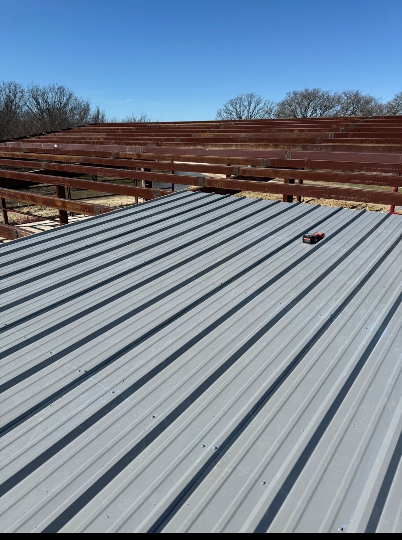 Corrugated metal roof under construction with steel framing and a clear blue sky