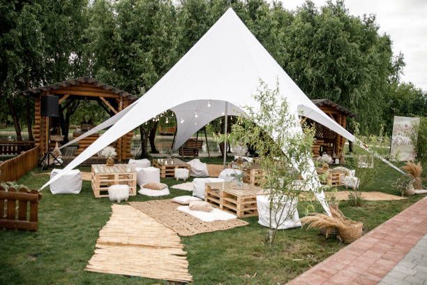 Outdoor event space with white tent, wooden seating, and garden setting.