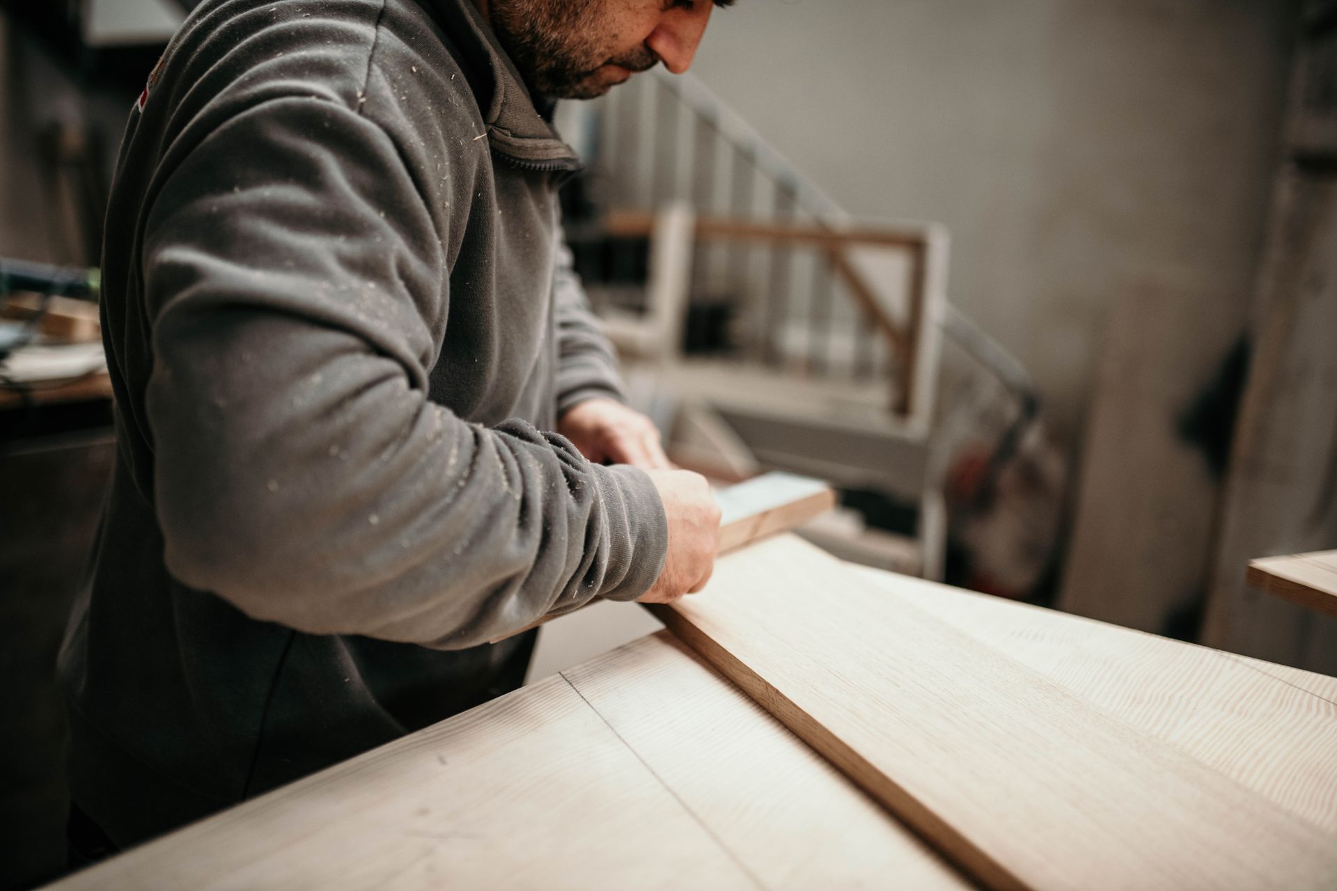 Falegname che leviga un'asse di legno in un laboratorio.