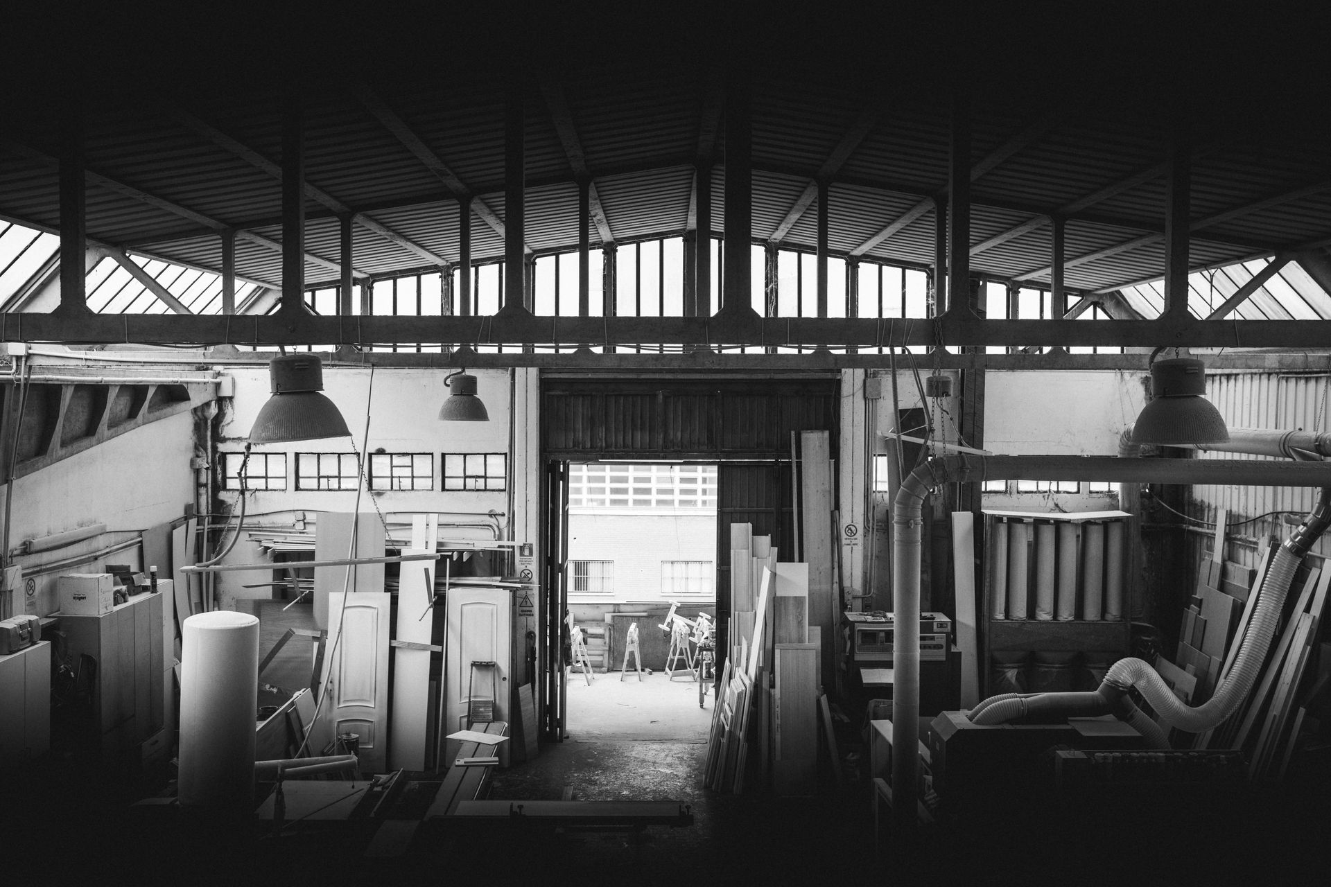 Foto in bianco e nero dell'interno di un'officina, con travi in ​​legno e luci soffuse.