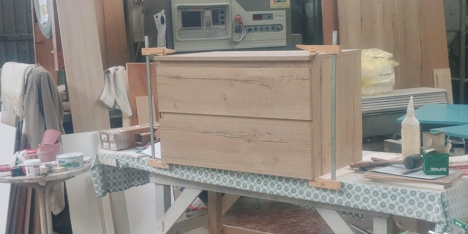 Una cassettiera in legno in costruzione in un laboratorio, tenuta insieme da morsetti.