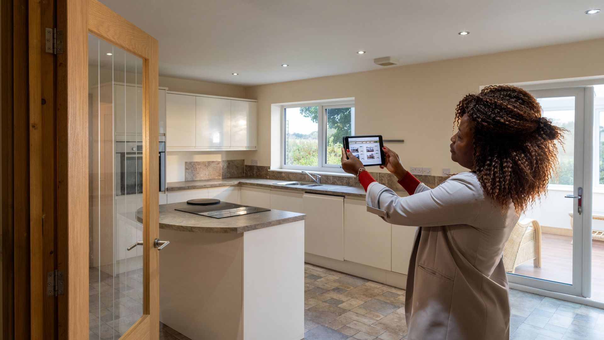 Female agent in the kitchen of a property with tablet, providing real estate appraisal services. Female agent in the kitchen of a property with tablet, providing real estate appraisal services.